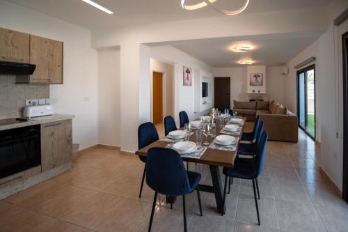 a dining room with a long table and blue chairs at Luxury Villa Agathoula in Protaras
