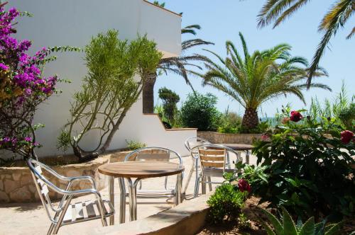 a patio with a table and chairs and palm trees at Sol y Mar in Playa Migjorn