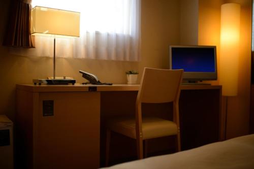 a desk with a computer and a chair in a hotel room at Montein Hotel in Kitakami
