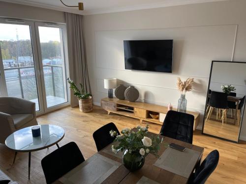 a living room with a table and chairs and a television at Sucha Street Apartments, Nowa Letnica,Gdańsk in Gdańsk