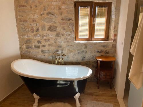 a bath tub in a bathroom with a stone wall at Castle Inn in Kaštela