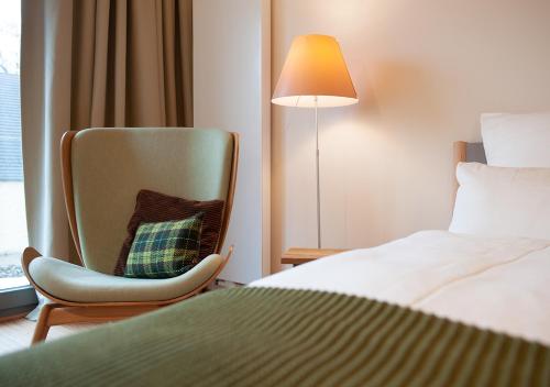 a room with a bed and a chair and a lamp at FELDGANG ein Gästehaus! in Upahl