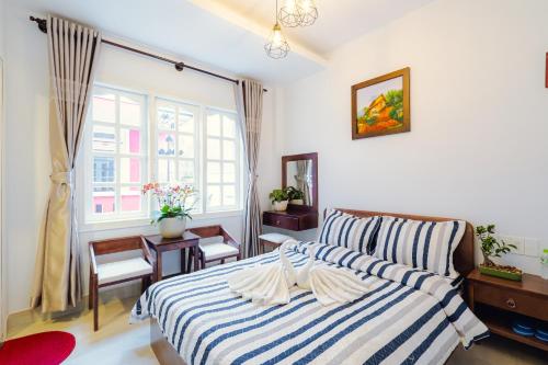 1 dormitorio con 1 cama con manta de rayas azul y blanco en Lovely House en Da Lat
