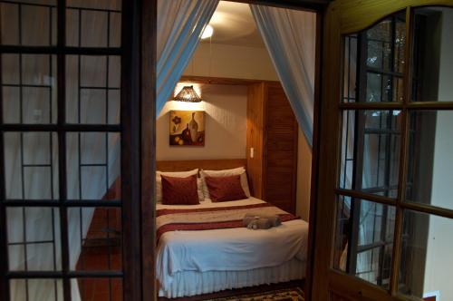 a bedroom with a bed in a room with windows at Woodpecker Inn in Richards Bay