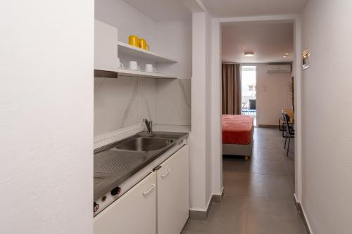 une cuisine blanche avec un évier et un couloir dans l'établissement Bemyguest Comfort Zefyros, à Neoi Poroi