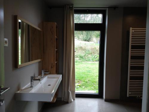 a bathroom with a sink and a mirror and a window at Ardennature vakantiehuizen met privé-sauna in La Roche-en-Ardenne