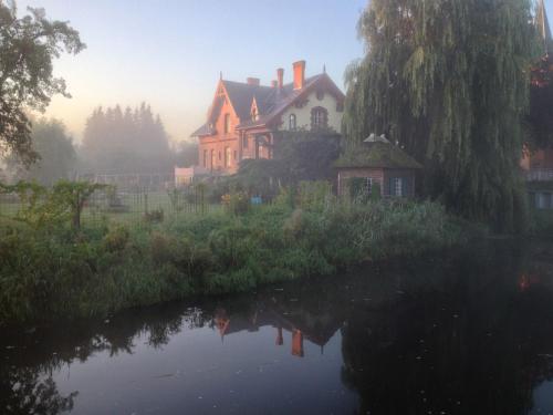 a house on the side of a river in the fog at B&B Mühlenvilla am Bützower Hafen in Bützow