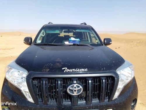 a black car parked in the sand in the desert at Bivouac ZAGORA in Zagora