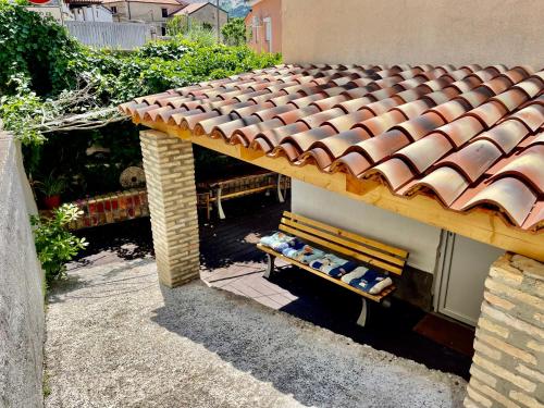 a bench sitting next to a building with a tiled roof at Apartments Rome in Baška