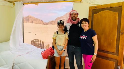 a man and two women standing in front of a bed at Rum Jordan camp and tours in Wadi Rum