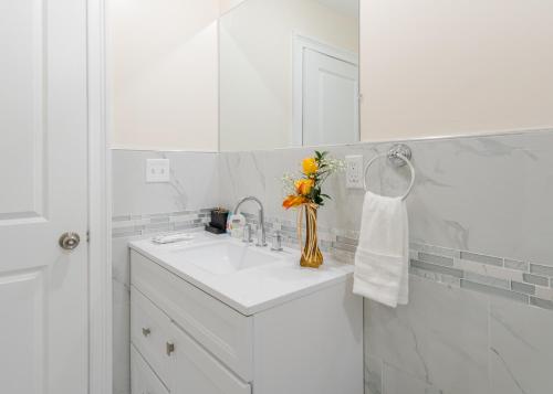 a white bathroom with a sink and a vase of flowers at 37-Greater Boston Cozy Townhouse in Quincy