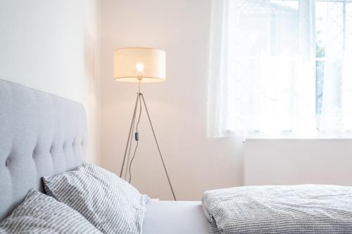a white bedroom with a bed and a lamp at OMA's Apartment in Haus GRETE in Bad Waltersdorf