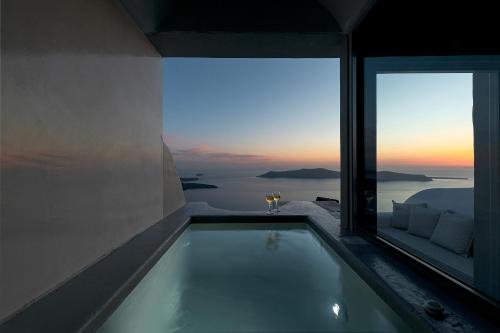 a bath tub in a room with a view of the ocean at Kaleidoscope Imerovigli Suites in Imerovigli