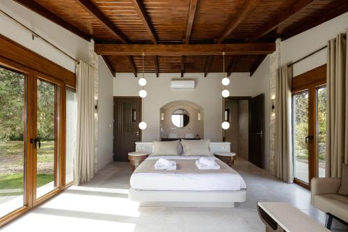 a bedroom with a large white bed and large windows at Alpha Estate & Spa in Rethymno Town