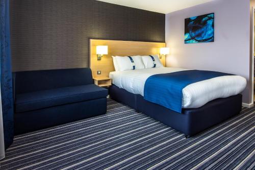 a hotel room with a bed and a couch at Holiday Inn Express Manchester Airport by IHG in Hale