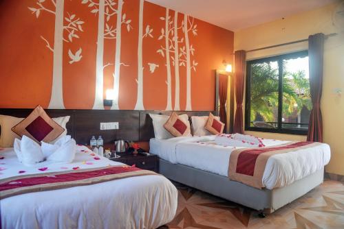 Duas camas num quarto com paredes cor de laranja em Vision Safari Pvt Ltd em Sauraha