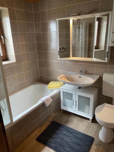 ein Badezimmer mit einer Badewanne, einem Waschbecken und einem WC in der Unterkunft Landhotel Sportalm in Philippsreut