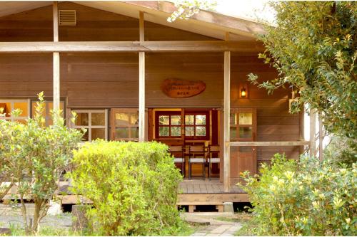 a large wooden house with a porch and a table at so-an morie in Higashiizu