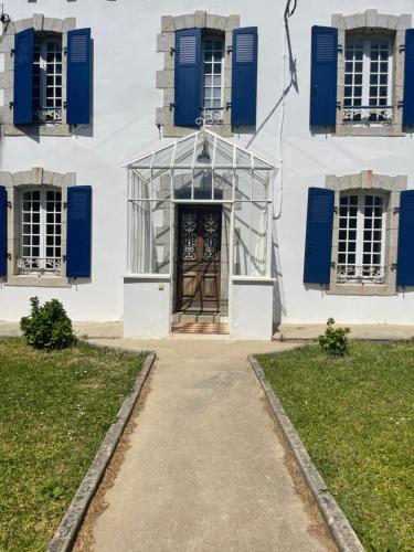 a building with blue shuttered windows and a door at Grande maison familiale, à 600m de la plage de Tahiti in Névez