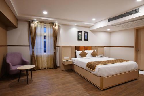 a hotel room with a bed and a chair at Soho Boutique Hotel in Mysore