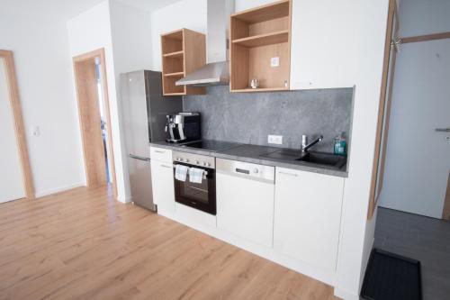 a kitchen with white cabinets and a wooden floor at Family XL - Bungalows in Lutzmannsburg