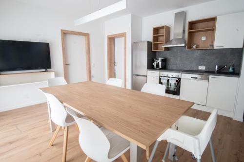 a kitchen and dining room with a wooden table and white chairs at Family XL - Bungalows in Lutzmannsburg