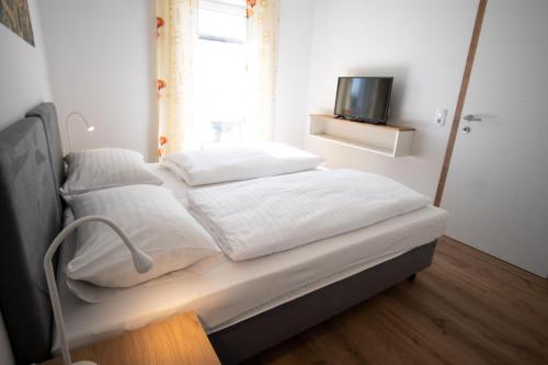 a bed with white sheets and pillows in a room at Family XL - Bungalows in Lutzmannsburg