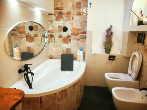 ein Badezimmer mit einer Badewanne, einem WC und einem Spiegel in der Unterkunft Spiaggia da Monic in Trevignano Romano