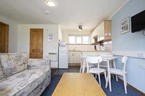 a living room with a couch and a table and a kitchen at Golden Sands Holiday Park in Kinmel Bay