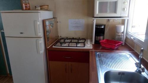 a small kitchen with a white refrigerator and a sink at Camping prés des Gorges du Verdon et Du Lac De Ste Croix 04500 Tout Equipé Confort Calme Lavande in Sainte-Croix-de-Verdon