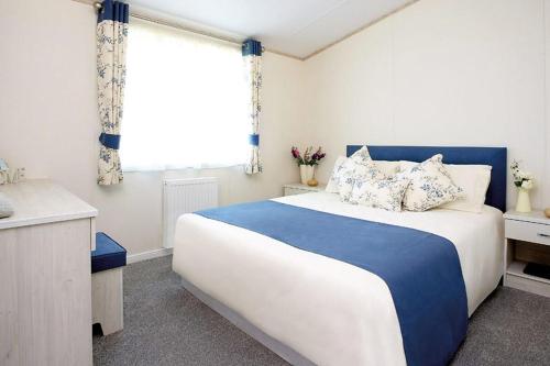 a bedroom with a blue and white bed and a window at Golden Sands Holiday Park in Kinmel Bay