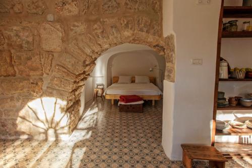 The Nest - A Romantic Vacation Home in Ein Kerem - Jerusalem في القدس: غرفة نوم بسرير وجدار حجري