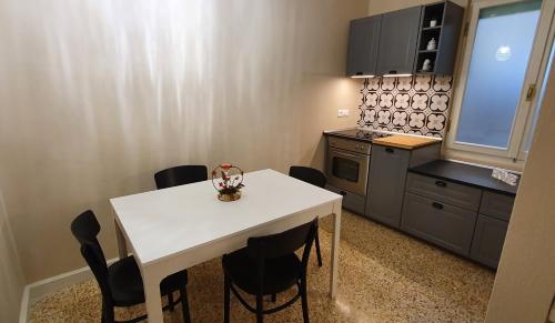 una pequeña cocina con mesa blanca y sillas negras en Appartamento in Piazza Nova, en Pratovecchio