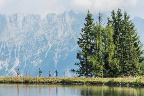 a group of people walking on a hill next to a body of water at Ferienwohnungen Salvenmoser Johanna in Scheffau am Wilden Kaiser