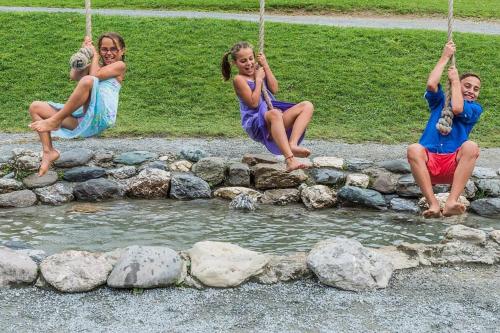 three girls sitting on a swing in a pond at Ferienwohnungen Salvenmoser Johanna in Scheffau am Wilden Kaiser