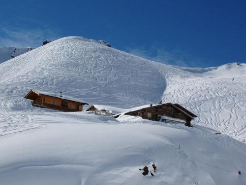 a cabin on a snow covered slope with a mountain at Ferienwohnungen Salvenmoser Johanna in Scheffau am Wilden Kaiser