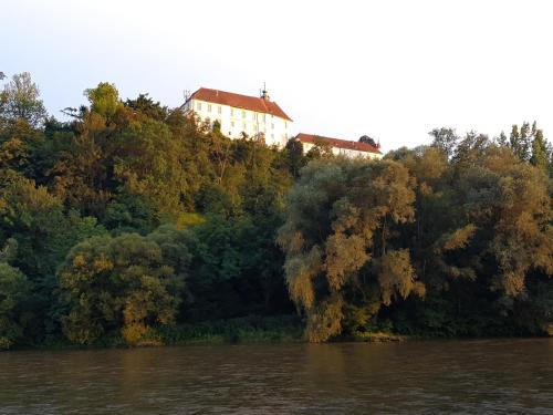a house on top of a hill next to a river at Fado Apartments Gornja Radgona in Gornja Radgona