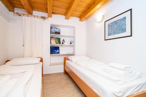 Habitación con 2 camas, paredes blancas y techos de madera. en Apartment Ribambit, en Dubrovnik
