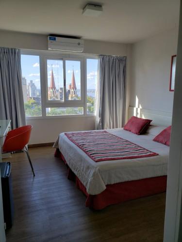 ポサーダスにあるHotel Continentalの大きなベッドと大きな窓のある寝室
