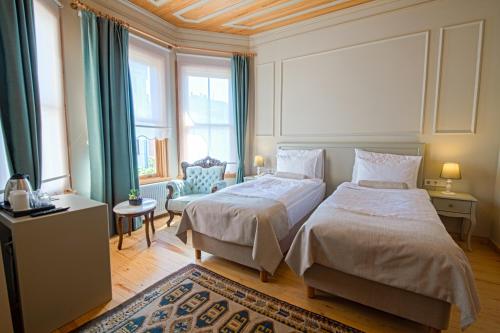 1 dormitorio con 2 camas, silla y ventanas en İkiz Konak Boutique Hotel, en Estambul