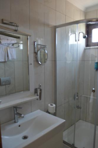 uma casa de banho com um lavatório e um chuveiro com um espelho. em BAL Mini Hotel em Tirebolu