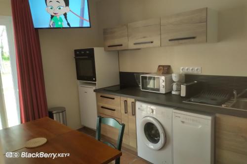 cocina con lavadora y mesa en Domaine de l'Hostreiere - Appartements, en Colleville-sur-Mer