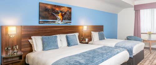 a hotel room with two beds and a painting on the wall at Last Drop Village Hotel & Spa in Bolton
