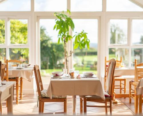 a dining room with tables and chairs and windows at Knoll Hill Farm, The Place To Stay in Frome