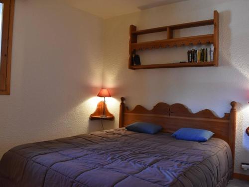 a bedroom with a bed with blue pillows and a lamp at Appartement 3 pièces, piscine, skis aux pieds, centre de Méribel - FR-1-180-136 in Méribel