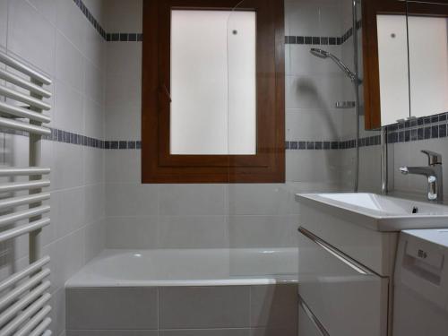 a white bathroom with a tub and a sink at Appartement 3 pièces, piscine, skis aux pieds, centre de Méribel - FR-1-180-136 in Méribel