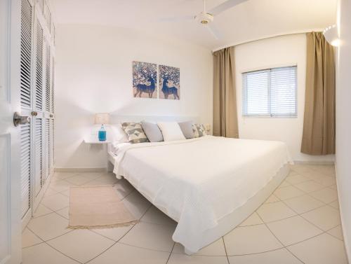 a white bedroom with a large bed and a window at Family Dominicus Apartment - Bayahibe in Bayahibe