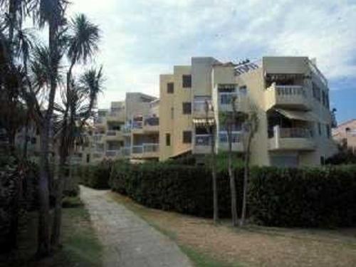 un bâtiment avec des palmiers devant un bâtiment dans l'établissement Studio cabine 4 pers, piscine, parking, proche plage, St Cyprien - FR-1-225D-152, à Saint Cyprien Plage