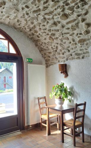 une table avec des chaises et une plante en pot au plafond dans l'établissement Auberge du Glandon, à Saint-Colomban-des-Villards