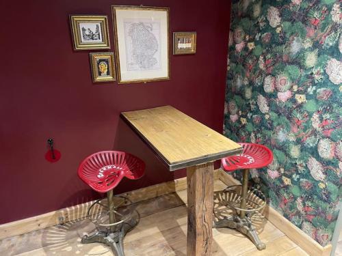 a table and two red stools in a room at The Fuggle in Whaplode